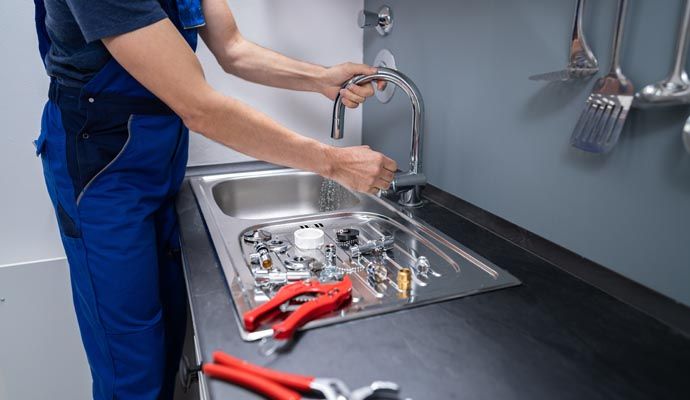 Professional plumber repairing kitchen sink Professional plumber repairing kitchen sink